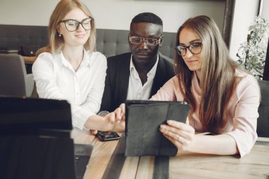 African man. Guy in a black suit. Students with a laptop. Girl in white blouse. International people in a cafe.