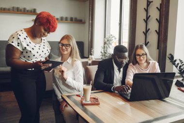 African man. Guy in a black suit. Students with a laptop. Girl in white blouse. International people in a cafe.