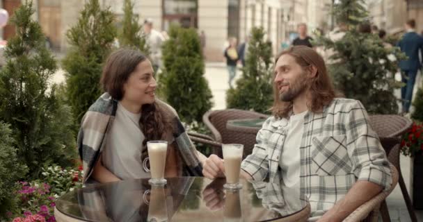 中等个子的白人青年男女坐在户外咖啡馆的桌旁 一边喝着咖啡 一边谈着话 一边笑着 — 图库视频影像