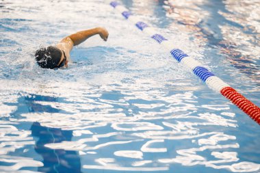 Photo of a man wearing special hat for swimming. Man swimming breaststroke in swimming pool. Professionale male swimmer training.
