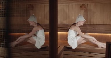 A beautiful woman wearing a white towel takes a sauna. Concept of: relax, vacation, wellness center.