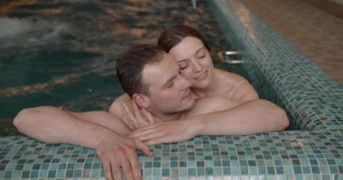 Young couple bathing together. Loving couple flirting in pool spa.