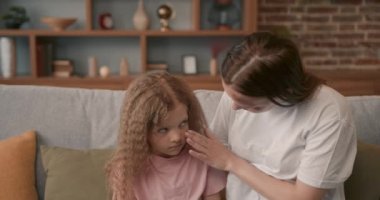 Caucasian girl kid sitting and crying on sofa while parents having fighting or quarrel conflict at home. Child hugging her toy, family violence concept.