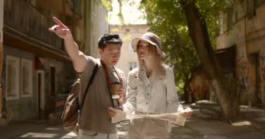 Young couple looking at map in the city. Honeymoon trip, backpacker tourist, historical city tourism, or summer holiday vacation travel concept. High Resolution.