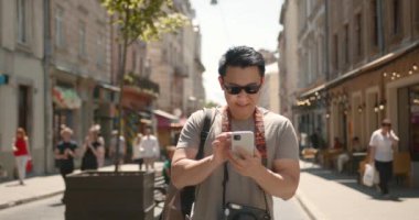 Handsome male tourist in glasses standing at old city street. Concept of travelling, tourism and photography