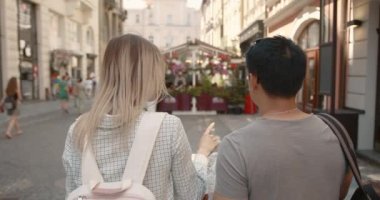 Young couple looking at map in the city. Honeymoon trip, backpacker tourist, historical city tourism, or summer holiday vacation travel concept. High Resolution.