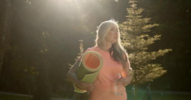 Olgun kadın parkta egzersiz yapmadan önce su içer. Sağlıklı yaşam tarzı kavramı.