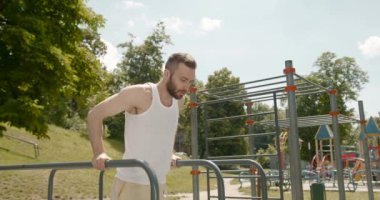 Genç sporcu paralel barlarda alıştırma yapıyor. Aktif yaşam tarzı. 4K.