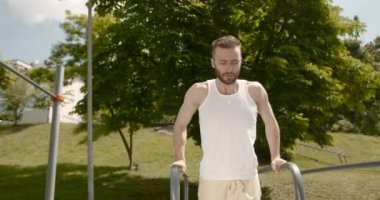 Genç sporcu paralel barlarda alıştırma yapıyor. Aktif yaşam tarzı. 4K.