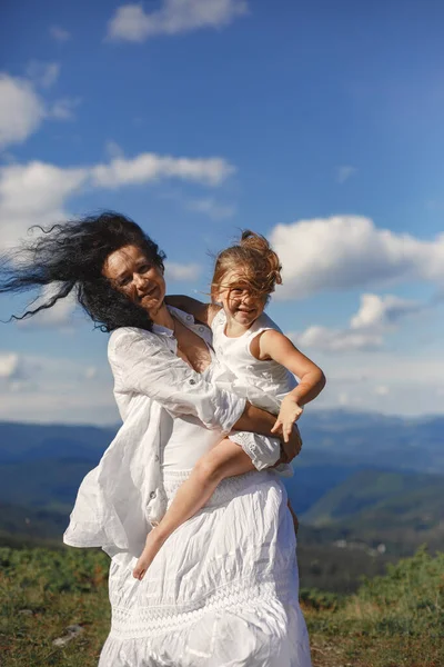 Stylish family in the mountains. Grandma and daughter on a sky background. Woman in a white dress.