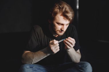 Uyuşturucu bağımlılığı konsepti. Genç hasta uyuşturucu bağımlısı. Tek başına oturuyor ve bir doz almak üzere..