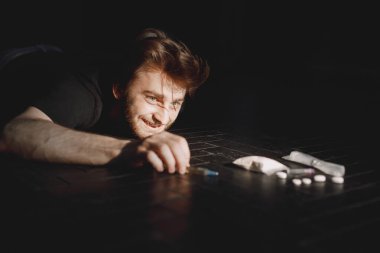 Zeminde uyuşturucu bağımlısı bir adam var. Keş el şırıngayı almaya çalışıyor..