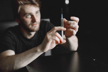 Uyuşturucu bağımlılığı konsepti. Genç hasta uyuşturucu bağımlısı. Tek başına oturuyor ve bir doz almak üzere..