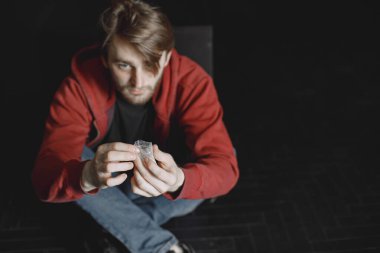 Kokain paketiyle yalnız oturan genç bağımlı adam.