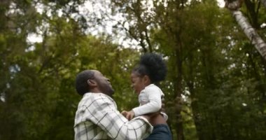 Happy affectionateb lack race family. Father playing with little daughter and walking in the park. Dad and cute child girl enjoy spending time together on outdoor weekend vacation.