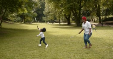 Parent having fun in a green sunny park. Smiling black mother playing enjoy warm summer day with cute daughter. Parenthood emotional bonding concept.