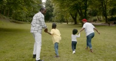 Black parents with kids on grass .Summer vacation on green meadow.People play run on grass.
