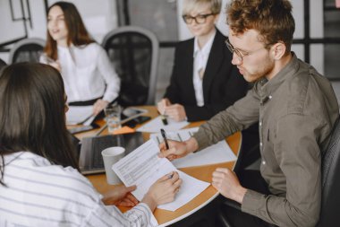 İnsanlar proje üzerinde çalışıyor. Masada oturan takım elbiseli erkekler ve kadınlar. İş adamları dizüstü bilgisayar kullanır..