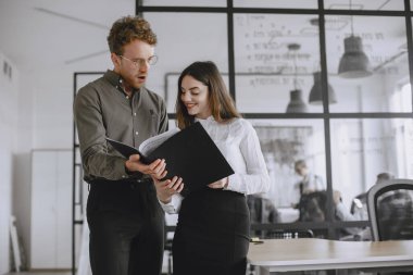 People are working on the project. Man and woman holding a folder. Employees in their office.