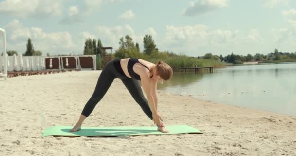 湖のそばのビーチで運動やトレーニングをする運動とスポーティ若い女性 魅力的なフィット白人女性 屋外で働く 健康的なライフスタイル — ストック動画