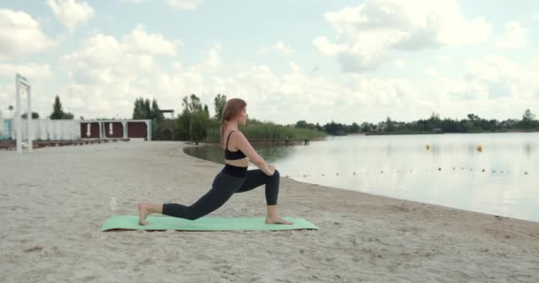 湖のそばのビーチで運動やトレーニングをする運動とスポーティ若い女性 魅力的なフィット白人女性 屋外で働く 健康的なライフスタイル — ストック動画