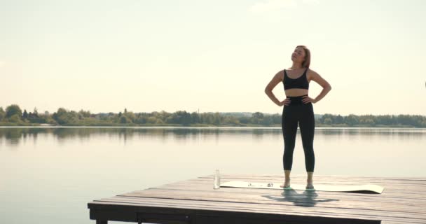 Ung Kvinna Som Kopplar Vid Sjön Yogamattan Utövar Yoga Tränar — Stockvideo