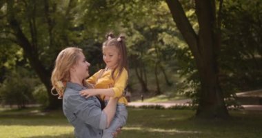 Birlikte tatilde parkta gülümseyen bir anne ve çocuk. Genç, mutlu, sevgi, ilgi ve özgürlük dolu bir kız. Mutluluk ve huzur için doğada bir tatil yaparken..