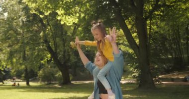 Birlikte tatilde parkta gülümseyen bir anne ve çocuk. Genç, mutlu, sevgi, ilgi ve özgürlük dolu bir kız. Mutluluk ve huzur için doğada bir tatil yaparken..