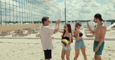 Voleybol takımı maçtan önce konuşuyor ve eğleniyor. Arkadaşlar hafta sonu plajda spor yapıyor..