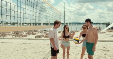 Voleybol takımı maçtan önce konuşuyor ve eğleniyor. Arkadaşlar hafta sonu plajda spor yapıyor..