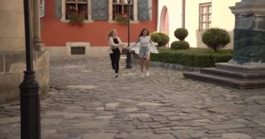 Caddenin karşısındaki kadın eşcinsel çift el ele tutuşuyor. Eski bir kasabada mutlu mesut koşuşturan iki şık kız. 4k ağır çekim .