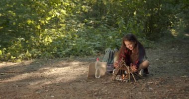 Küçük kız ateş için çubuk koyuyor. Kamp kavramı. Boş zaman ve doğa yolculuğu..