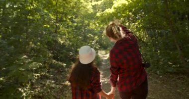 Güneşli bir günde, güzel bir yaz ormanında annesiyle el ele tutuşan kız. Seyahat, aile doğada boş zaman geçirir, eğlenir ve dinlenir, birlikte hafta sonu geçirirler..