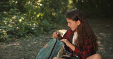 Yaz ormanında tek başına yürüyüş yapan genç bir kız. Ormanın ortasında yerde oturan ve sırt çantasından turist malzemelerini çıkaran bir genç. Doğanın keşfi, aktif hobiler konsepti.