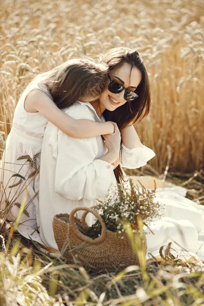 在阳光灿烂的日子里 一个身穿白衣的年轻母亲和女儿在麦田里的照片 布鲁内特的母亲和她的小女儿摆姿势拍照 妈妈拥抱她的女儿 — 图库照片