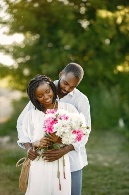 Genç Afrikalı çift bir tarlada romantik bir şekilde kucaklaşıyor. Çiçekli bir tarlada genç aşıklar.
