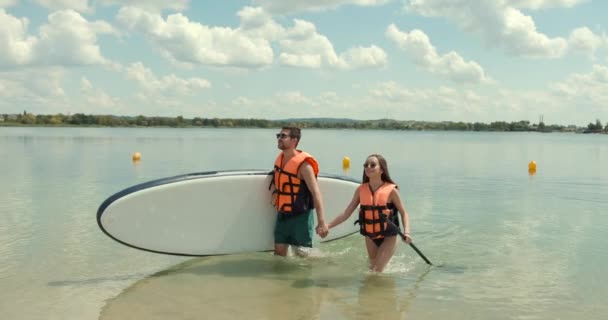 코카서스 남녀가 수영용 가지고 호수에서 수영을 스포츠를 파도타기를 친구들 — 비디오
