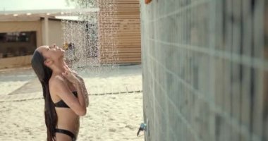 Duş alan genç bir kadın. Güzel kız saçını yıkıyor ve yüzdükten sonra ferahlatıcı bir duşun keyfini çıkarıyor..