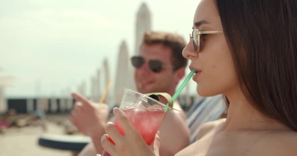和平夫妇日光浴和举行鸡尾酒会 年轻夫妇在度假胜地海滩晒日光浴和喝彩色鸡尾酒 度蜜月的情人 — 图库视频影像