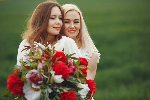 Women with flowers. Ladies in a white dress. Women in a summer field.