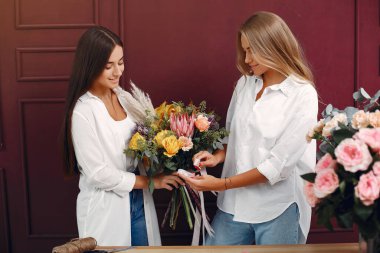 Çiçekli Florisr. Kadınlar buket yapar. İki kız çalışıyor.