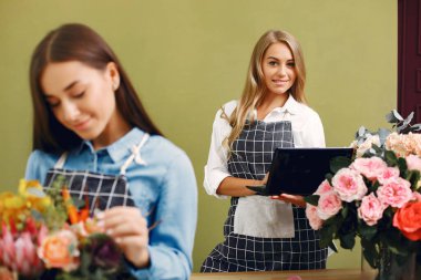 Çiçekli çiçekçi. Kadın buket yapıyor. Kız bir buket alır.