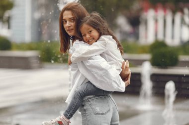 Family near the city fountain. Mother with gaughter playing with water.