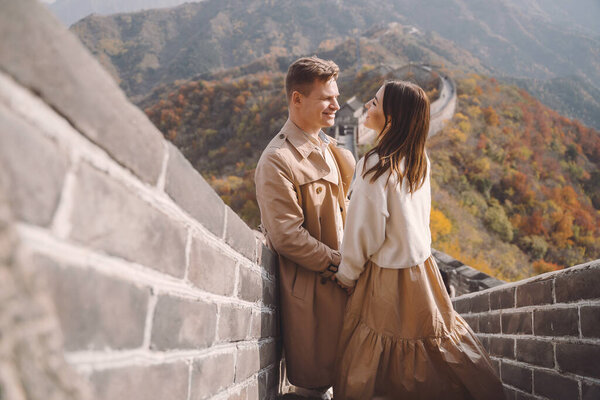 beautiful young couple showing affection on the Great Wall of China. Newly married couple on their honemoon to Great Wall near Beijing China. Stylish couple exploring one of the wonders of the world