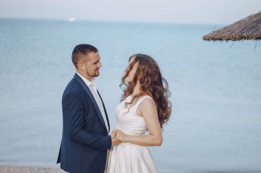 Sahilde genç kocasıyla beyaz elbiseli genç güzel uzun saçlı gelin
