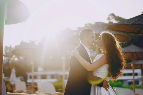 ビーチで彼女の若い夫と白いドレスの美しい若い長髪の花嫁 — ストック写真