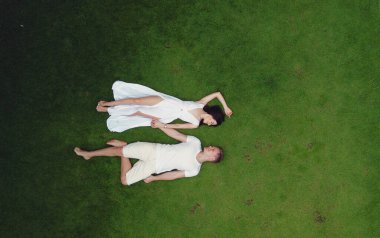 Tatilde bir çift. İnsanlar çimlerin üzerinde yalan söyler. Beyaz elbiseli kadın. Bir İHA 'dan ateş etmek.