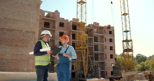 Dos Constructores Caucásicos Con Cascos Pie Edificio Construcción Hablando — Vídeos de Stock