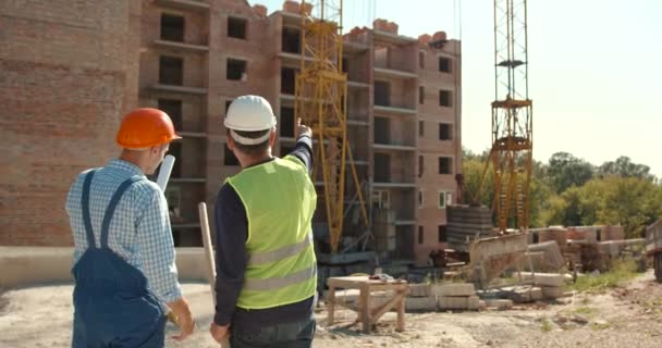 Dos Trabajadores Construcción Con Sombreros Chalecos Reflectantes Discutiendo Planes Ingeniería — Vídeos de Stock