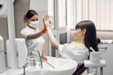 Dişçi koltuğundaki kadın. Kız bir diş hekimi tarafından muayene ediliyor. Doktor beş hasta veriyor.